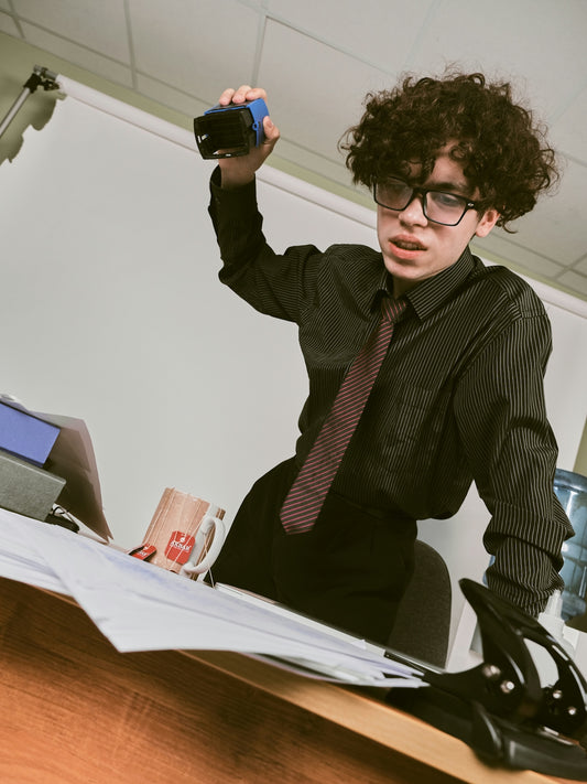 a man wearing glasses and a tie holding a camera