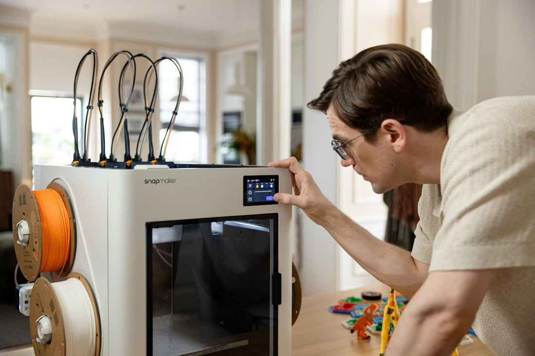 Man operating a 3D printer with spools of filament.