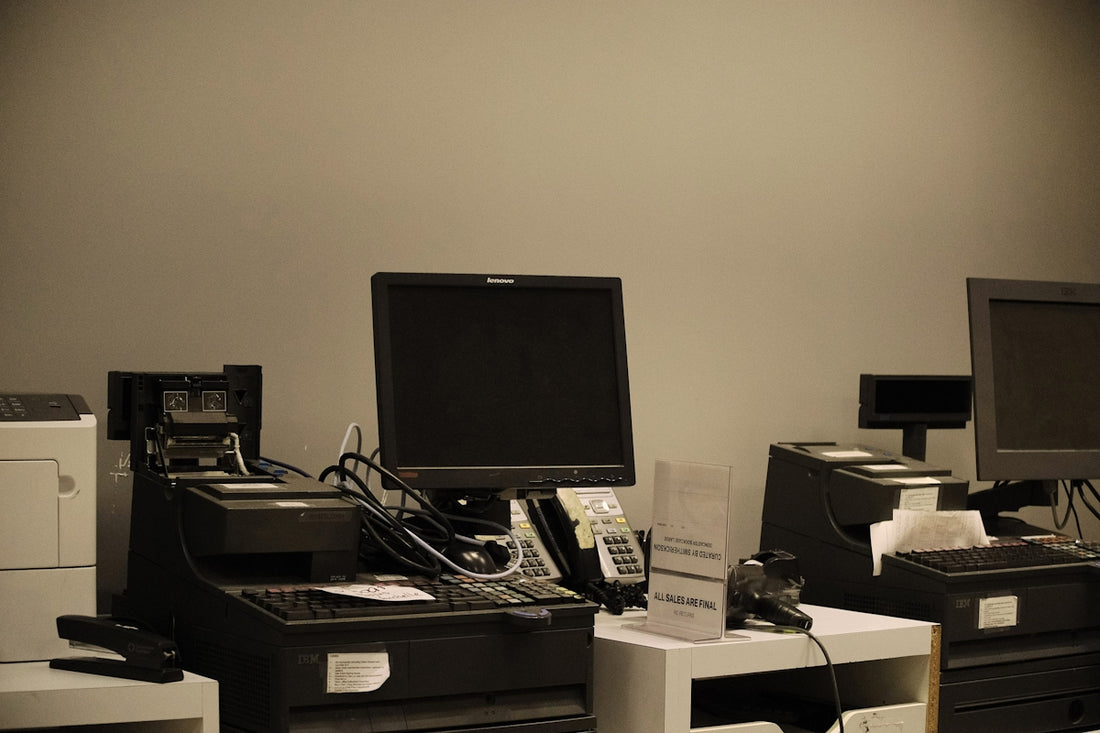 Multiple cash registers with computer monitors at a checkout counter.